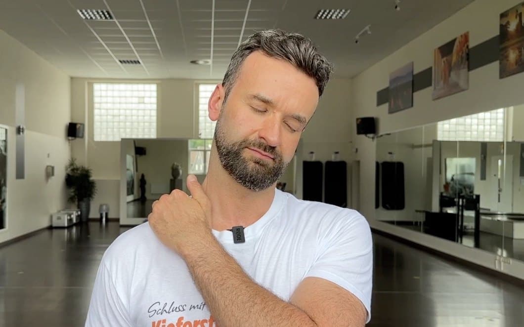 Robert Lazik neigt den Kopf zur Seite und ertastet mit der Hand den seitlichen Nacken